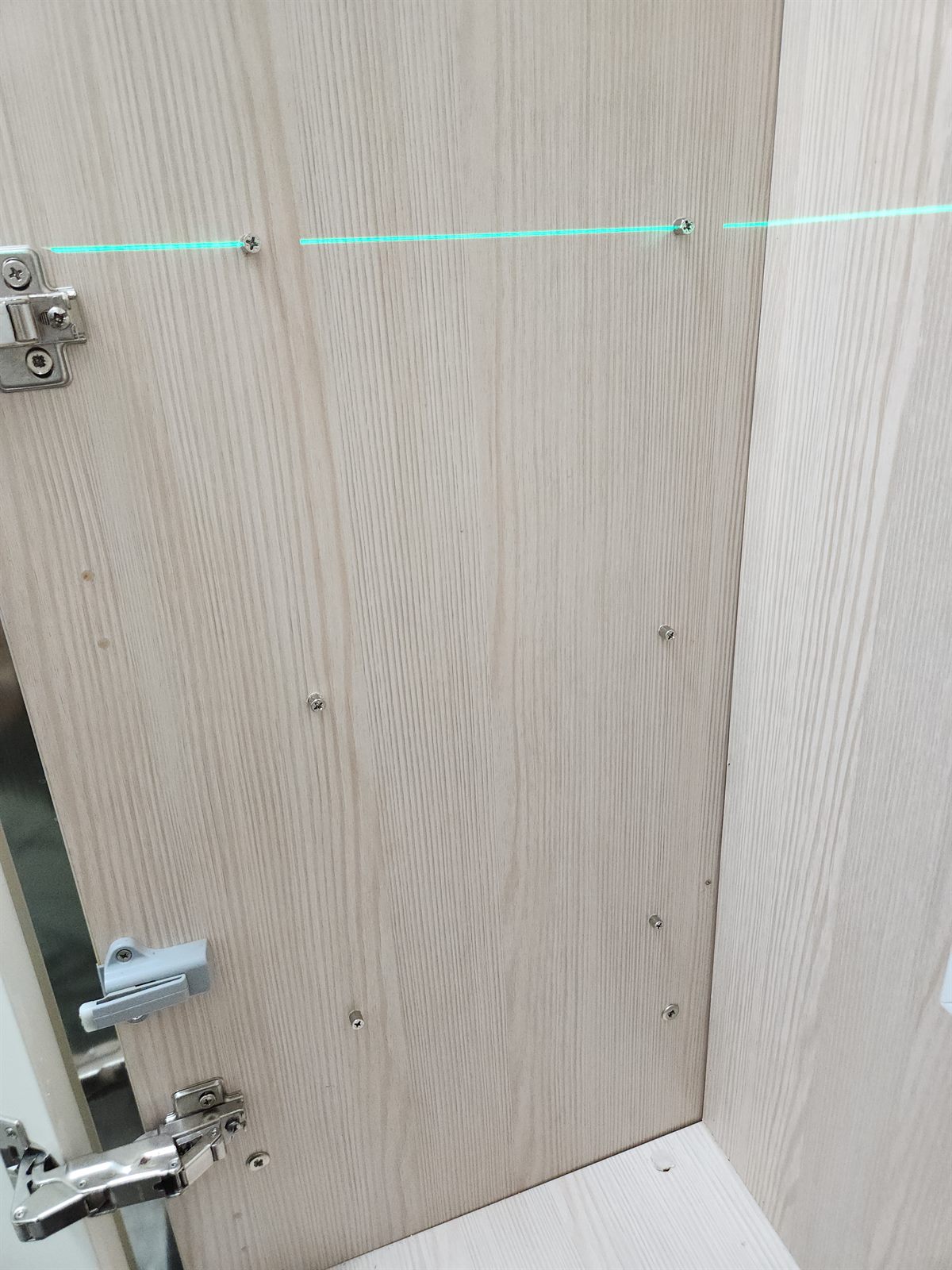 레이저 수평기 초록 선에 맞춰 선반 위치를 잡는 모습